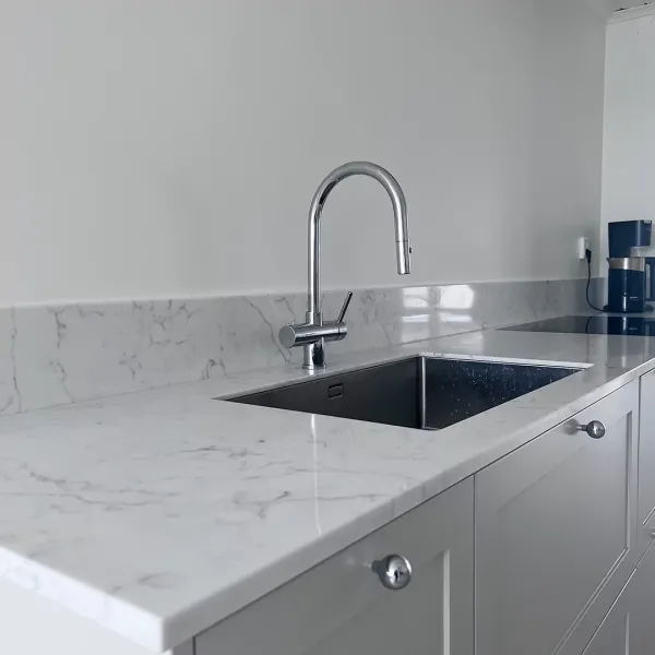 Rostfri diskho med knoppar och blandare i krom kompletterar bänkskivan och stänkskyddet i marmorimitation.